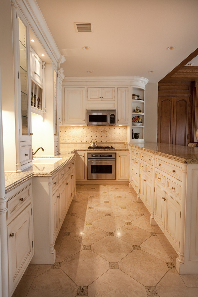 Huge elegant galley marble floor open concept kitchen photo in Los Angeles with a drop-in sink, recessed-panel cabinets, white cabinets, granite countertops, beige backsplash, porcelain backsplash, stainless steel appliances and an island