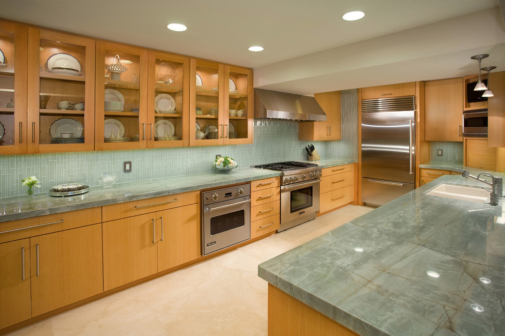 Esempio di una cucina design con lavello sottopiano, ante lisce, ante in legno chiaro, paraspruzzi verde, elettrodomestici in acciaio inossidabile e paraspruzzi con piastrelle di vetro