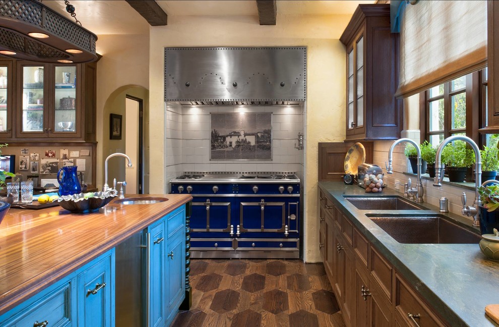 Diseño de cocina mediterránea con armarios tipo vitrina, encimera de madera, electrodomésticos de colores, puertas de armario azules y fregadero bajoencimera