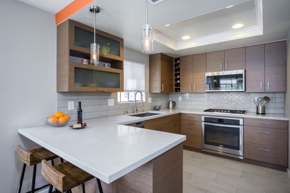 This is an example of a small retro u-shaped kitchen/diner in Los Angeles with a submerged sink, flat-panel cabinets, medium wood cabinets, engineered stone countertops, beige splashback, ceramic splashback, medium hardwood flooring, brown floors and white worktops.