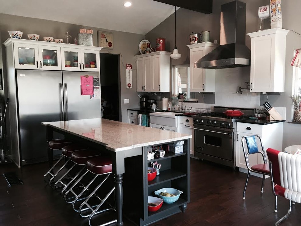 シアトルにある中くらいなエクレクティックスタイルのおしゃれなキッチン (アンダーカウンターシンク、グレーのキャビネット、御影石カウンター、白いキッチンパネル、サブウェイタイルのキッチンパネル、シルバーの調理設備、濃色無垢フローリング) の写真