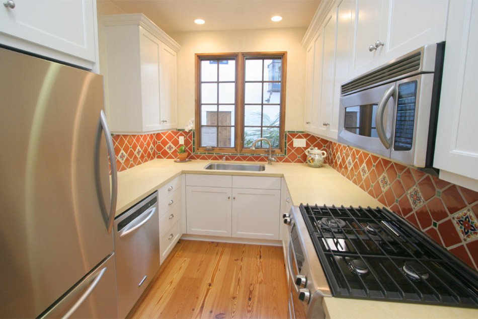 Exempel på ett avskilt, litet medelhavsstil u-kök, med en undermonterad diskho, skåp i shakerstil, vita skåp, bänkskiva i kvarts, flerfärgad stänkskydd, stänkskydd i mosaik, rostfria vitvaror, ljust trägolv och brunt golv