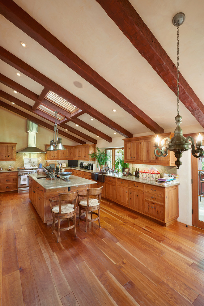 Example of a large southwest l-shaped medium tone wood floor kitchen design in Santa Barbara with a farmhouse sink, flat-panel cabinets, light wood cabinets, marble countertops, stone slab backsplash, stainless steel appliances and an island