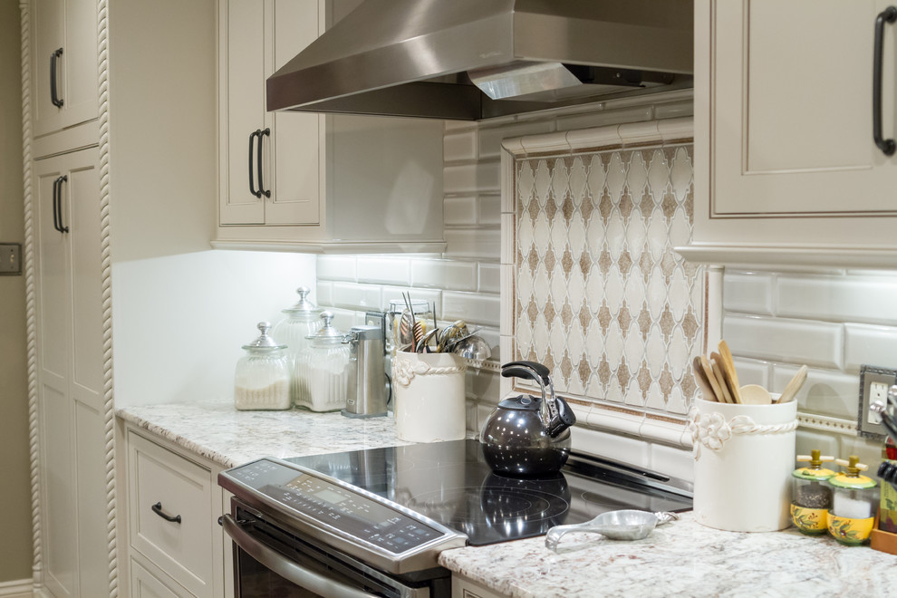 ニューオリンズにある低価格の中くらいなトランジショナルスタイルのおしゃれなキッチン (エプロンフロントシンク、インセット扉のキャビネット、白いキャビネット、御影石カウンター、緑のキッチンパネル、サブウェイタイルのキッチンパネル、シルバーの調理設備) の写真
