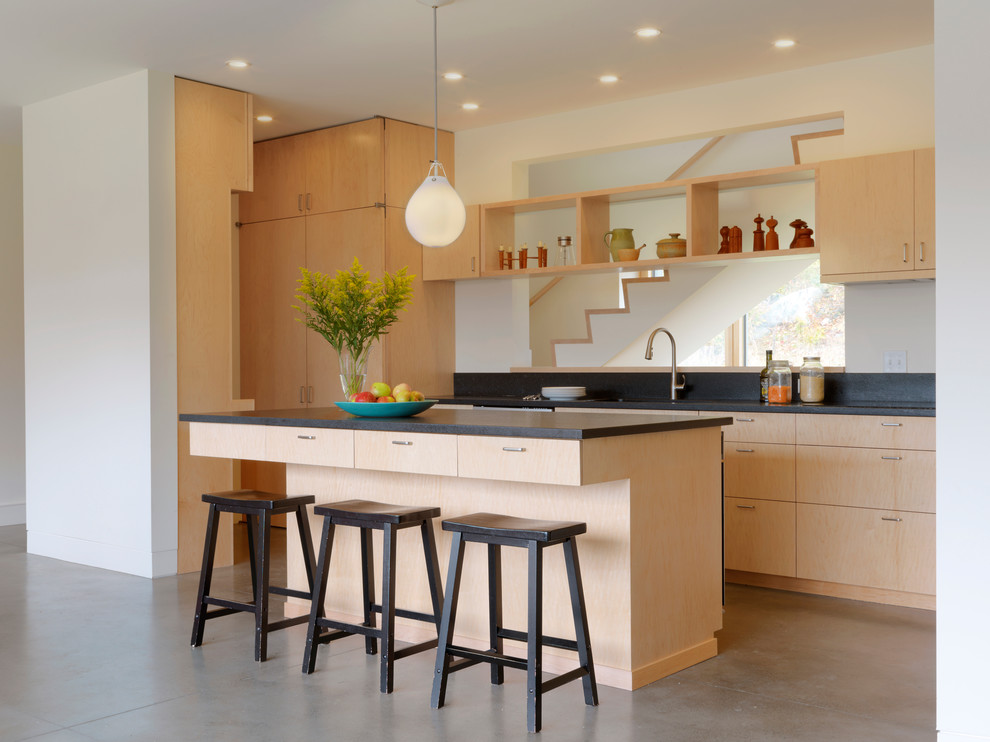 Kitchen - contemporary concrete floor kitchen idea in Burlington with flat-panel cabinets, light wood cabinets, black backsplash and an island