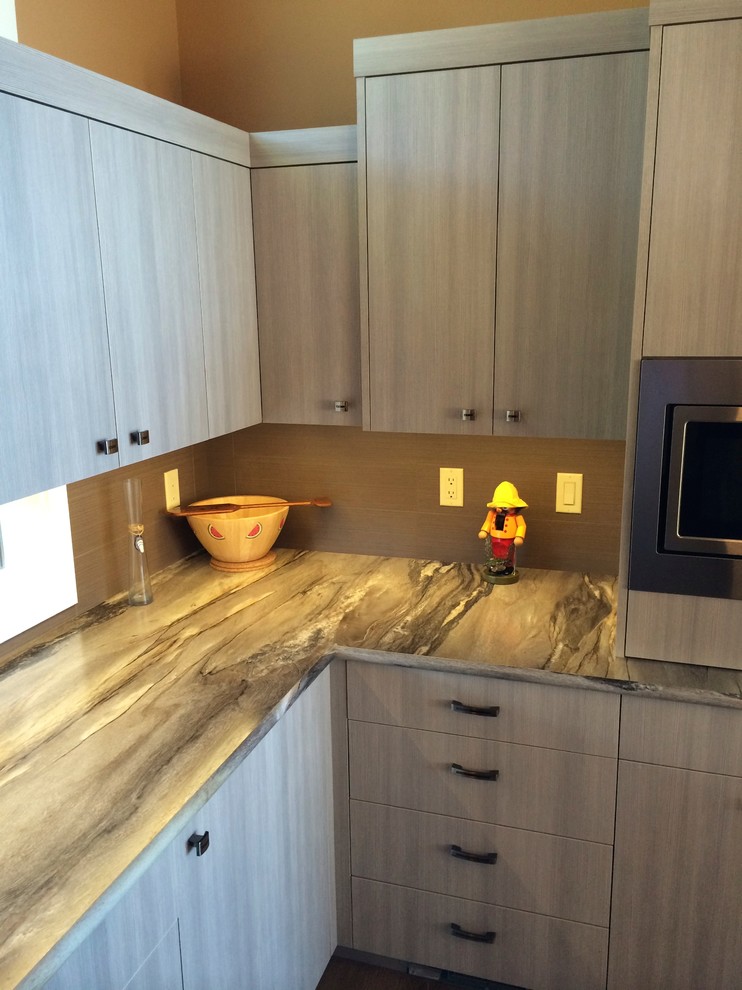 Diseño de cocina contemporánea con armarios con paneles lisos, puertas de armario grises, encimera de laminado, salpicadero marrón y electrodomésticos de acero inoxidable