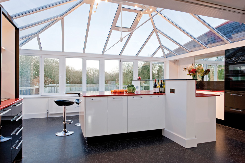 Example of a trendy kitchen design in Devon with white cabinets, an island, flat-panel cabinets and red countertops