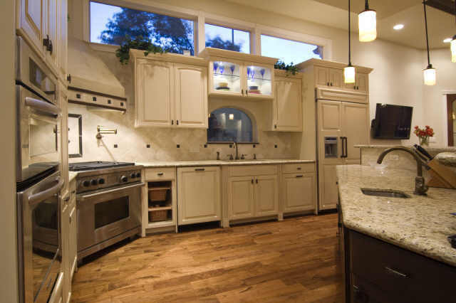 Zweizeilige, Geräumige Klassische Wohnküche mit Unterbauwaschbecken, profilierten Schrankfronten, weißen Schränken, Granit-Arbeitsplatte, Küchenrückwand in Beige, Rückwand aus Keramikfliesen, Elektrogeräten mit Frontblende, hellem Holzboden und Kücheninsel in Houston