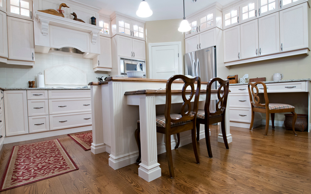 Mid-sized elegant l-shaped medium tone wood floor eat-in kitchen photo in Edmonton with an undermount sink, shaker cabinets, white cabinets, wood countertops, white backsplash, stainless steel appliances, an island and ceramic backsplash