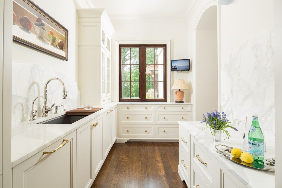 Immagine di una cucina mediterranea con lavello sottopiano, ante con riquadro incassato, ante bianche, paraspruzzi bianco e pavimento in legno massello medio
