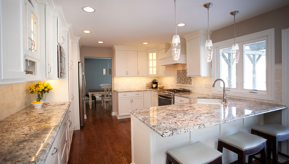 Example of a mid-sized transitional u-shaped dark wood floor eat-in kitchen design in Chicago with an undermount sink, shaker cabinets, white cabinets, granite countertops, beige backsplash, stone tile backsplash and stainless steel appliances