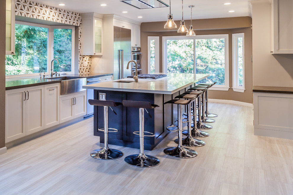 Example of a large transitional single-wall porcelain tile eat-in kitchen design in San Francisco with a farmhouse sink, shaker cabinets, white cabinets, quartz countertops, beige backsplash, stone tile backsplash, stainless steel appliances and an island