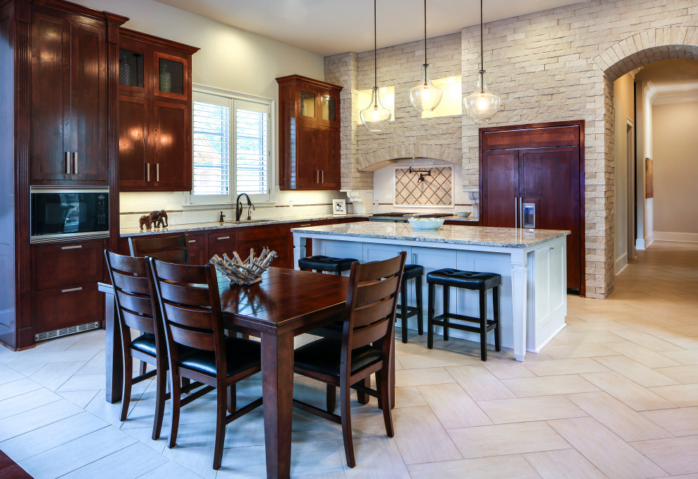 Example of a mid-sized transitional l-shaped porcelain tile eat-in kitchen design with an undermount sink, recessed-panel cabinets, dark wood cabinets, granite countertops, white backsplash, stainless steel appliances and an island
