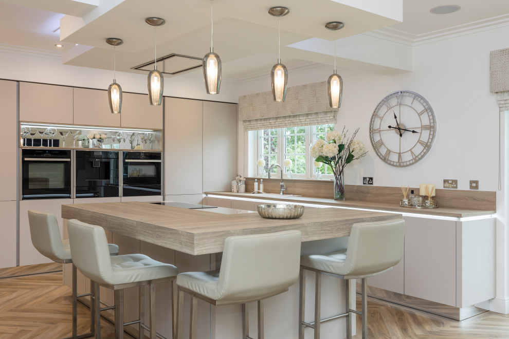Photo of a large contemporary l-shaped enclosed kitchen in Other with flat-panel cabinets, beige cabinets, engineered stone countertops, black appliances, laminate floors, an island and white worktops.