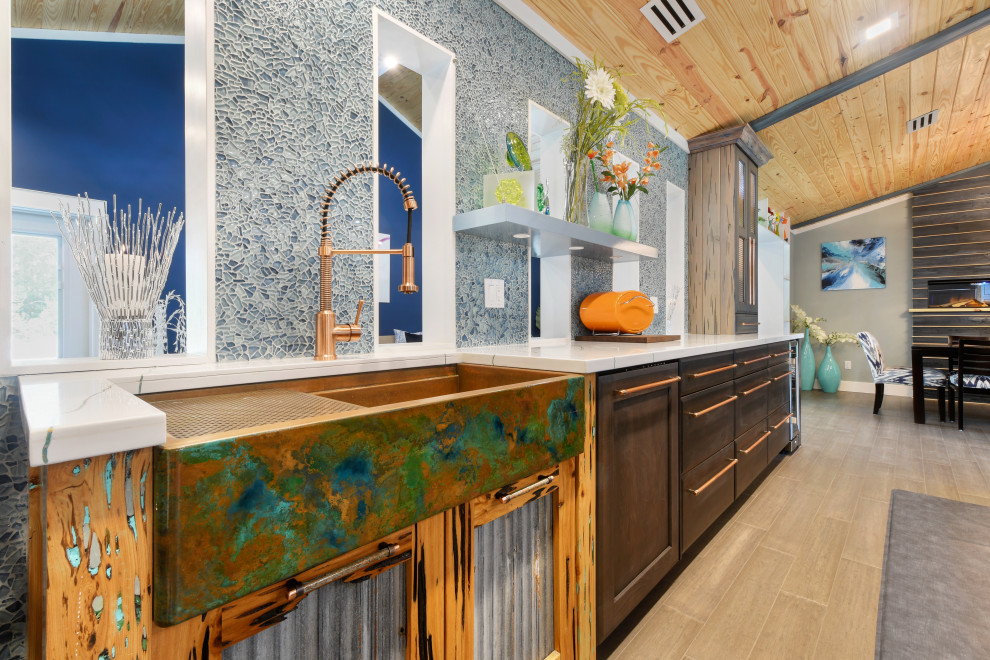 Inspiration for a large eclectic l-shaped bamboo floor and brown floor eat-in kitchen remodel in Miami with a farmhouse sink, raised-panel cabinets, brown cabinets, solid surface countertops, blue backsplash, glass sheet backsplash, stainless steel appliances, an island and white countertops