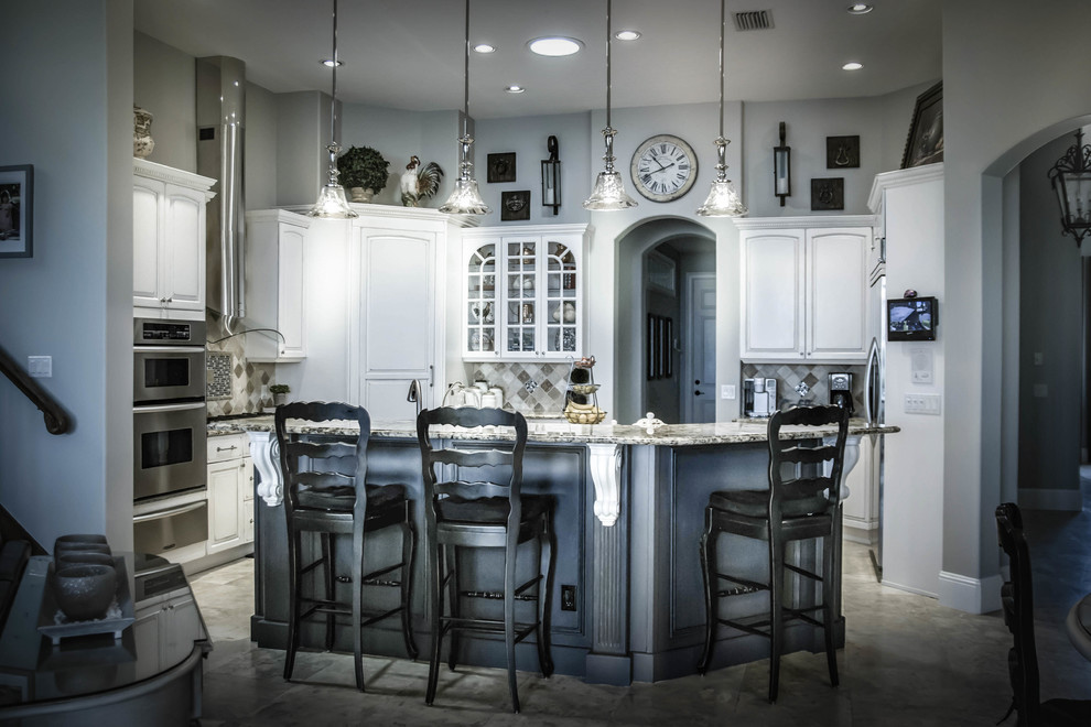 Inredning av ett klassiskt stort kök, med vita skåp, flera köksöar, marmorbänkskiva, grått stänkskydd, luckor med upphöjd panel, stänkskydd i keramik, rostfria vitvaror och klinkergolv i porslin