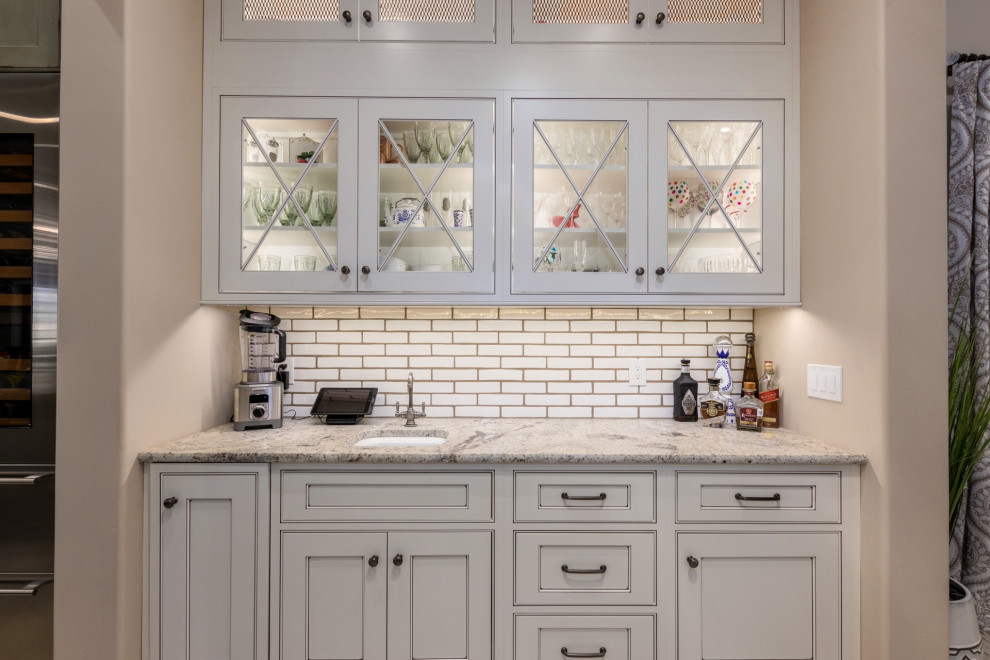 Cette image montre une cuisine rustique avec un évier encastré, des portes de placard blanches, un plan de travail en granite, une crédence blanche, un électroménager en acier inoxydable et îlot.
