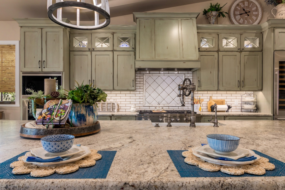 Immagine di un cucina con isola centrale country con lavello stile country, ante verdi, top in granito, paraspruzzi bianco e elettrodomestici in acciaio inossidabile