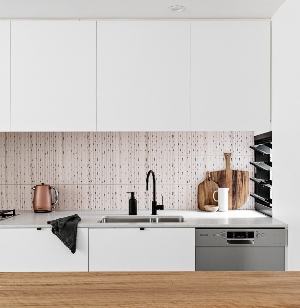 Bild på ett litet funkis brun brunt kök, med en undermonterad diskho, vita skåp, bänkskiva i kvarts, rosa stänkskydd, stänkskydd i keramik, rostfria vitvaror, terrazzogolv, en köksö och grått golv