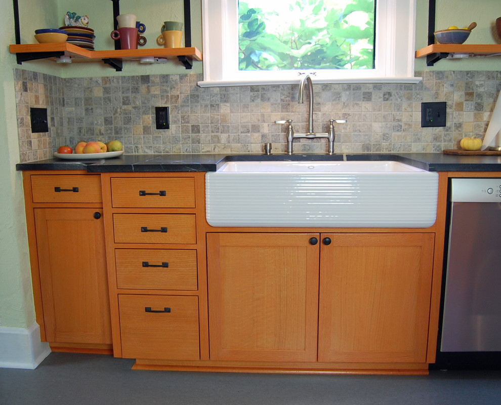 Bild på ett mellanstort amerikanskt parallellkök, med en rustik diskho, skåp i shakerstil, skåp i ljust trä, bänkskiva i täljsten, beige stänkskydd, stänkskydd i stenkakel, rostfria vitvaror, linoleumgolv, en köksö och svart golv