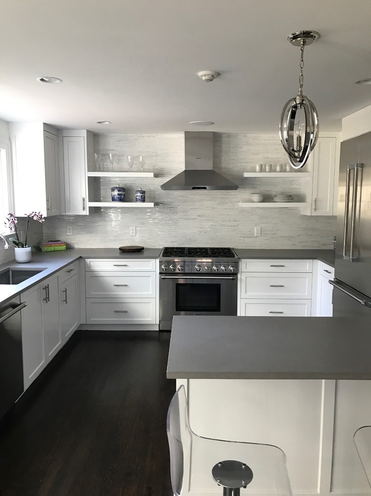 Mid-sized transitional l-shaped medium tone wood floor and gray floor enclosed kitchen photo in Orange County with an undermount sink, shaker cabinets, white cabinets, concrete countertops, white backsplash, marble backsplash, stainless steel appliances and a peninsula