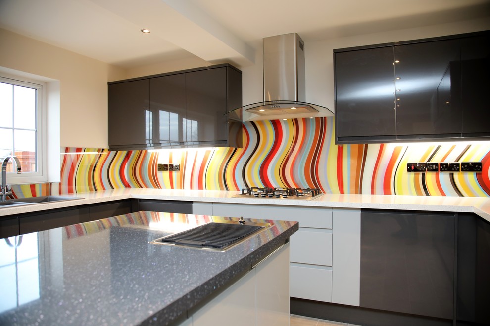 This is an example of an expansive contemporary open plan kitchen in Cheshire with flat-panel cabinets, grey cabinets, multi-coloured splashback, glass sheet splashback and multiple islands.