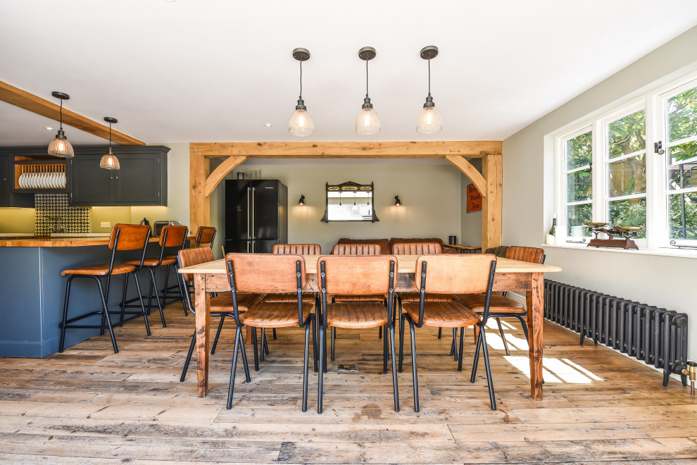 Cette photo montre une grande salle à manger ouverte sur le salon tendance avec un sol en bois brun et un sol marron.
