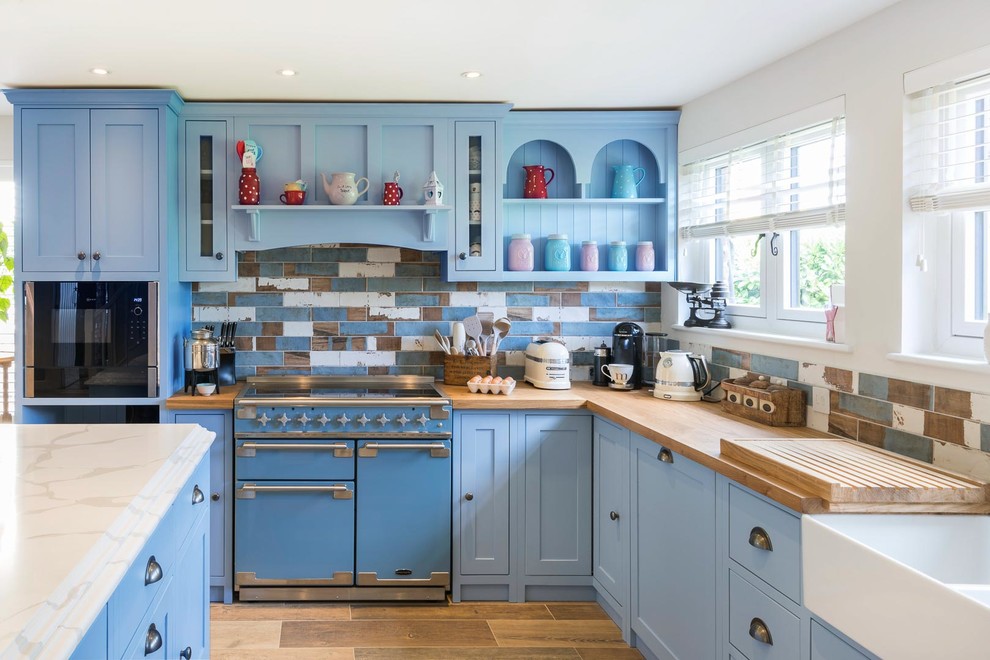 Photo of a country kitchen/diner in Kent with shaker cabinets, an island and blue worktops.
