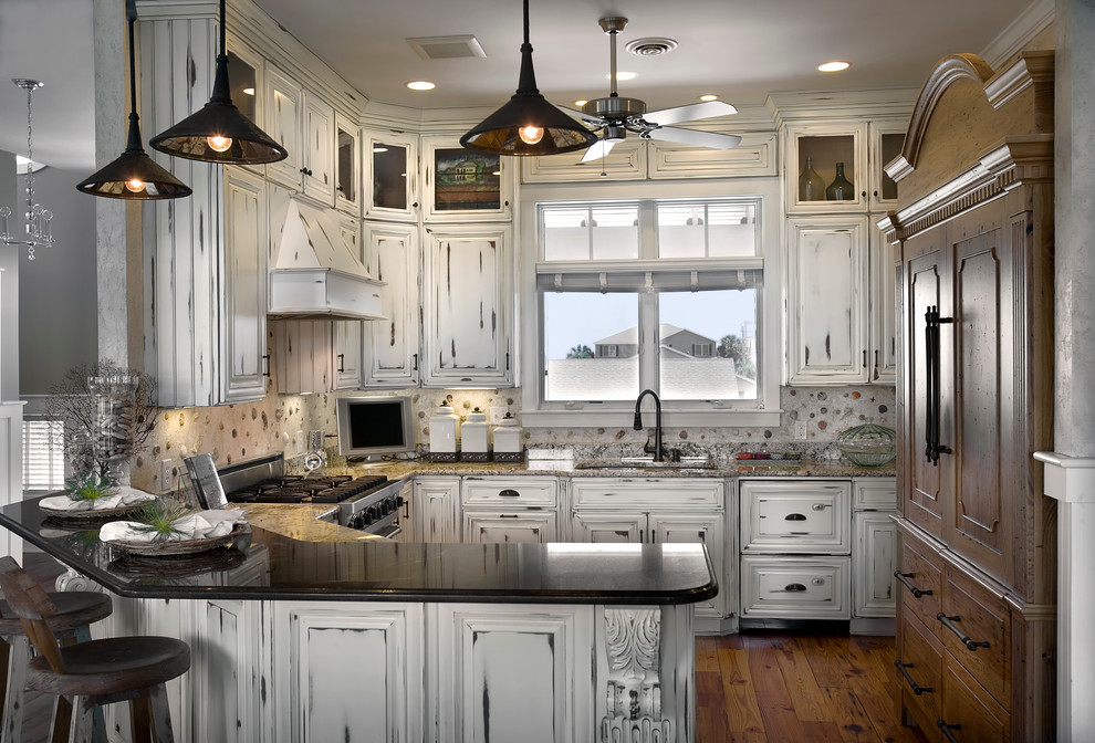 This is an example of a beach style u-shaped kitchen in Charleston with raised-panel cabinets and distressed cabinets.