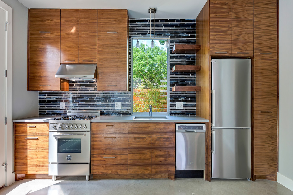 Inspiration for a contemporary single-wall kitchen remodel in Austin with an undermount sink, flat-panel cabinets, medium tone wood cabinets, black backsplash and stainless steel appliances