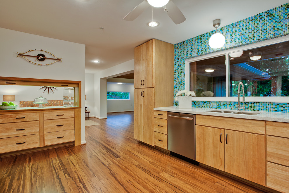 This is an example of a large midcentury u-shaped kitchen in Dallas with mosaic tiled splashback, multi-coloured splashback, light wood cabinets, flat-panel cabinets, a submerged sink, engineered stone countertops, stainless steel appliances, bamboo flooring, a breakfast bar and brown floors.