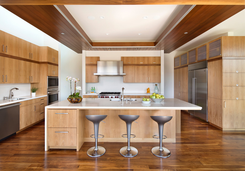 Offene Moderne Küche in U-Form mit Unterbauwaschbecken, flächenbündigen Schrankfronten, hellbraunen Holzschränken, Küchenrückwand in Weiß, Küchengeräten aus Edelstahl, braunem Holzboden, Kücheninsel und braunem Boden in San Francisco