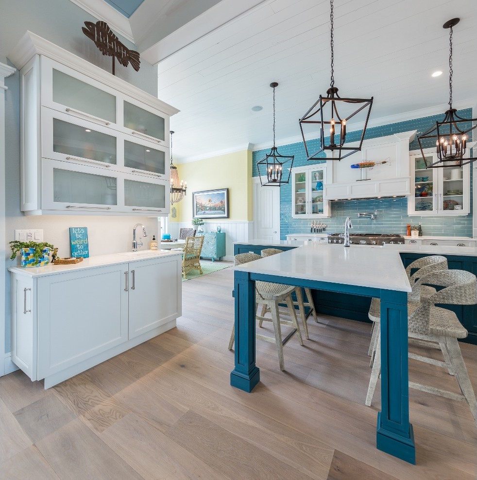 Design ideas for a medium sized coastal u-shaped kitchen/diner in Tampa with shaker cabinets, white cabinets, blue splashback, stainless steel appliances, medium hardwood flooring, an island, a belfast sink, composite countertops and wood splashback.