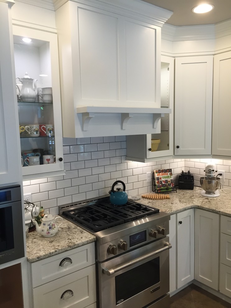 Photo of a medium sized country l-shaped enclosed kitchen in Atlanta with a submerged sink, shaker cabinets, white cabinets, granite worktops, white splashback, metro tiled splashback, stainless steel appliances, an island, brown floors and brown worktops.