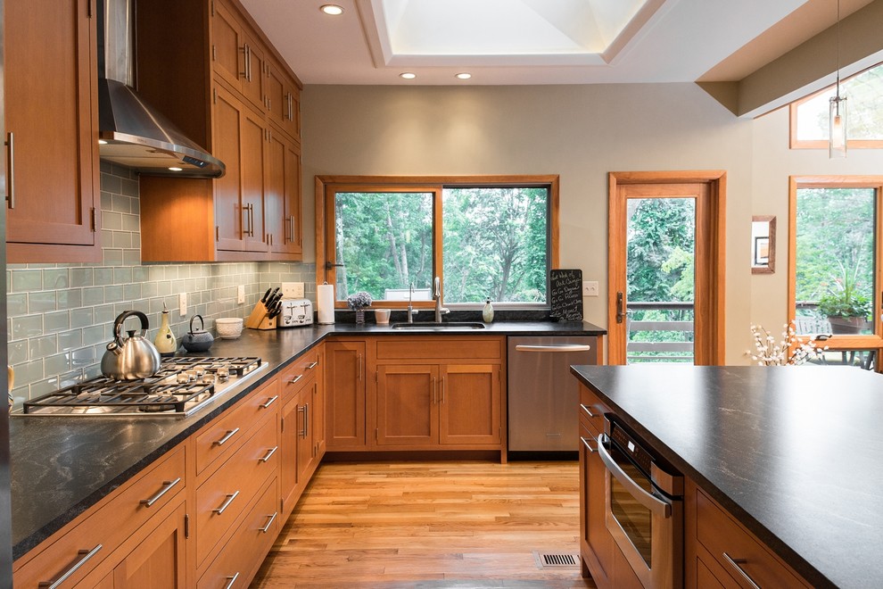 Example of a large trendy l-shaped light wood floor open concept kitchen design in New York with an undermount sink, shaker cabinets, light wood cabinets, granite countertops, gray backsplash, glass tile backsplash, stainless steel appliances and an island