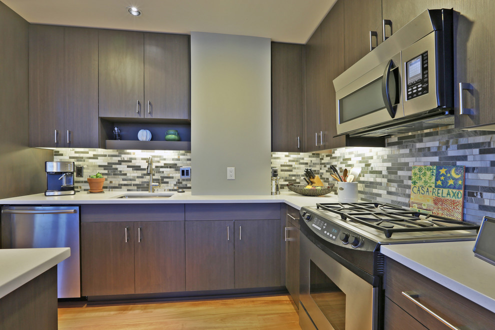 Modern inredning av ett mellanstort kök, med släta luckor, grå skåp, flerfärgad stänkskydd, rostfria vitvaror, en köksö, en undermonterad diskho, stänkskydd i stenkakel och ljust trägolv