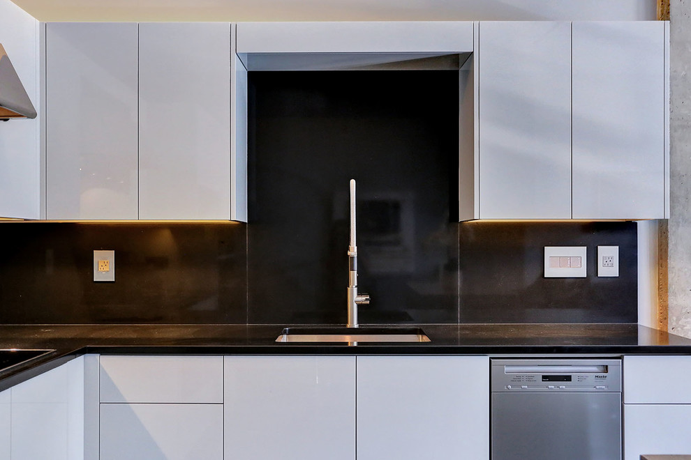 Foto på ett litet funkis kök, med en undermonterad diskho, släta luckor, bänkskiva i kvarts, svart stänkskydd, rostfria vitvaror, mörkt trägolv, vita skåp, stänkskydd i stenkakel och en köksö