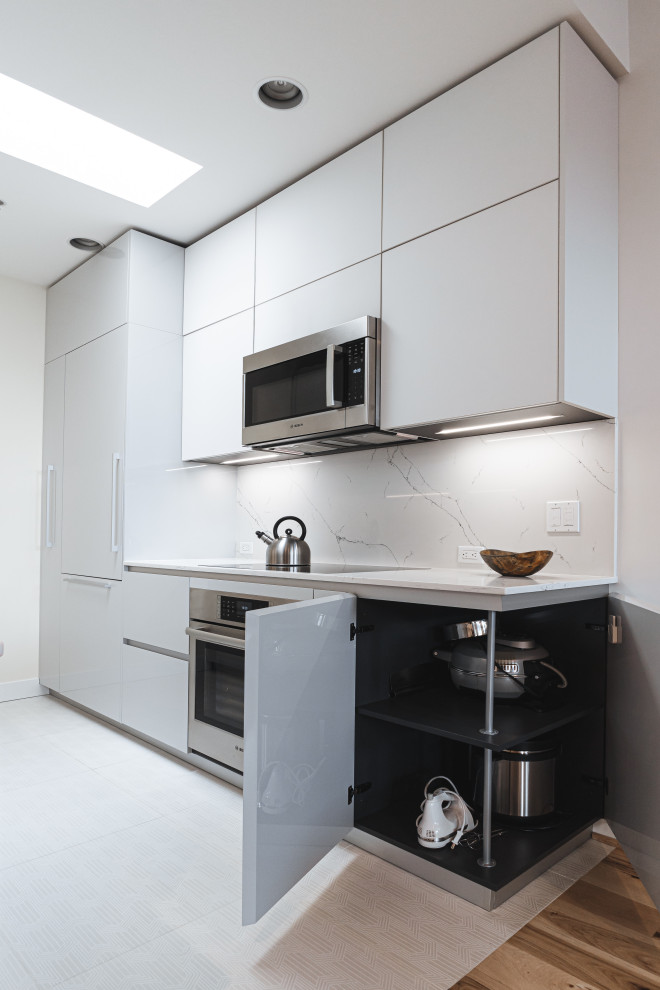 Modern inredning av ett litet vit vitt kök, med en undermonterad diskho, släta luckor, grå skåp, bänkskiva i kvarts, vitt stänkskydd, integrerade vitvaror, klinkergolv i keramik och vitt golv