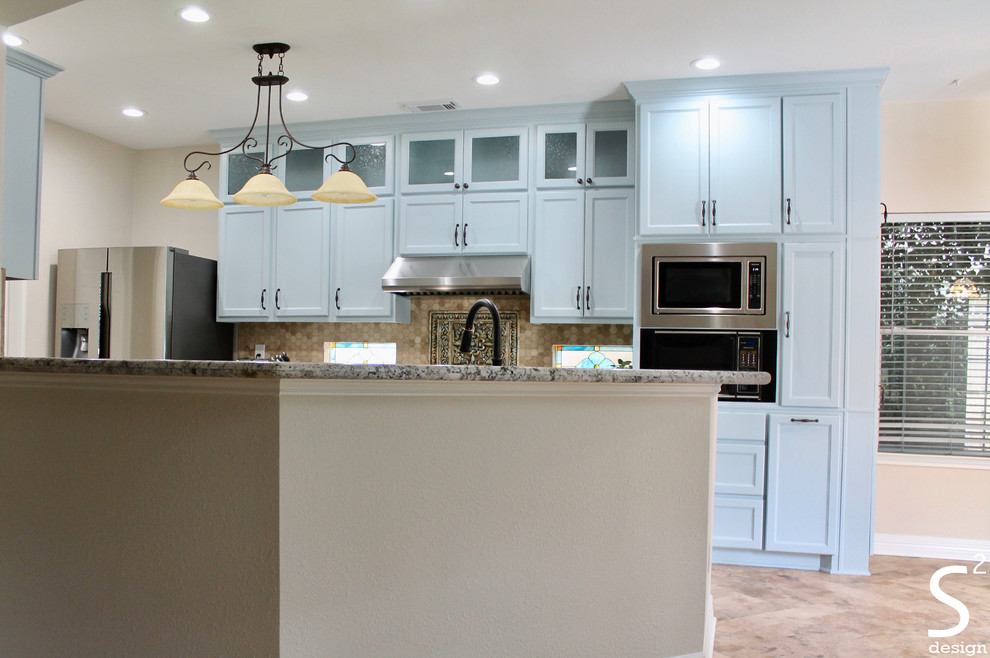 Bild på ett mellanstort eklektiskt flerfärgad flerfärgat kök och matrum, med en undermonterad diskho, luckor med infälld panel, blå skåp, granitbänkskiva, beige stänkskydd, stänkskydd i travertin, rostfria vitvaror, vinylgolv, en köksö och beiget golv