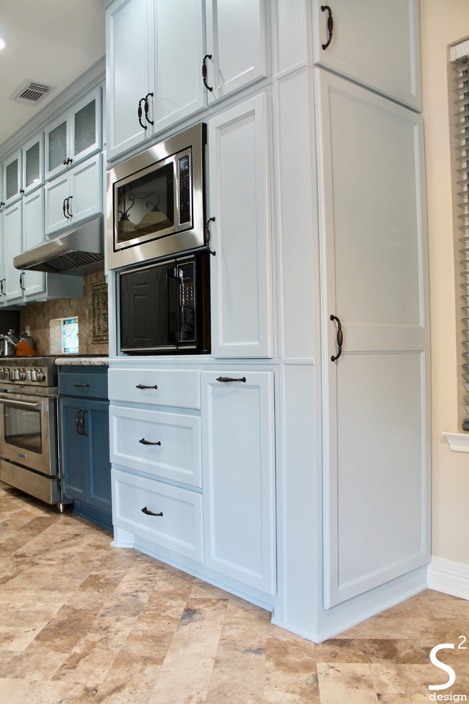 Foto på ett mellanstort eklektiskt flerfärgad kök och matrum, med en undermonterad diskho, luckor med infälld panel, blå skåp, granitbänkskiva, beige stänkskydd, stänkskydd i travertin, rostfria vitvaror, vinylgolv, en köksö och beiget golv