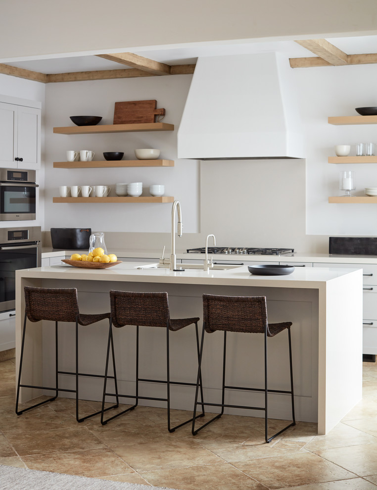 Idee per una cucina a L stile marino di medie dimensioni con nessun'anta, ante in legno chiaro, paraspruzzi bianco, pavimento beige e top bianco