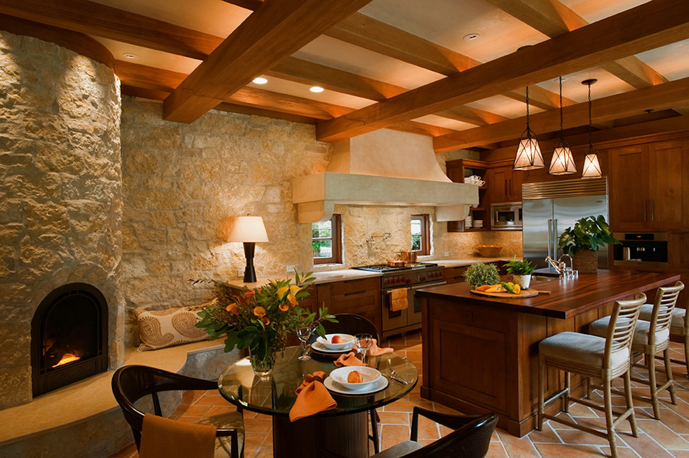 Foto på ett medelhavsstil vit kök, med en undermonterad diskho, skåp i shakerstil, skåp i mellenmörkt trä, marmorbänkskiva, en köksö och brunt golv