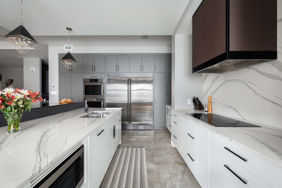 Large contemporary l-shaped open plan kitchen in Ottawa with a submerged sink, flat-panel cabinets, grey cabinets, engineered stone countertops, white splashback, stone slab splashback, stainless steel appliances, ceramic flooring, an island, grey floors and white worktops.