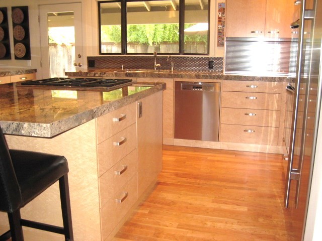 Photo of a medium sized contemporary open plan kitchen in Sacramento with a submerged sink, flat-panel cabinets, light wood cabinets, granite worktops, brown splashback, metal splashback, stainless steel appliances, medium hardwood flooring and an island.