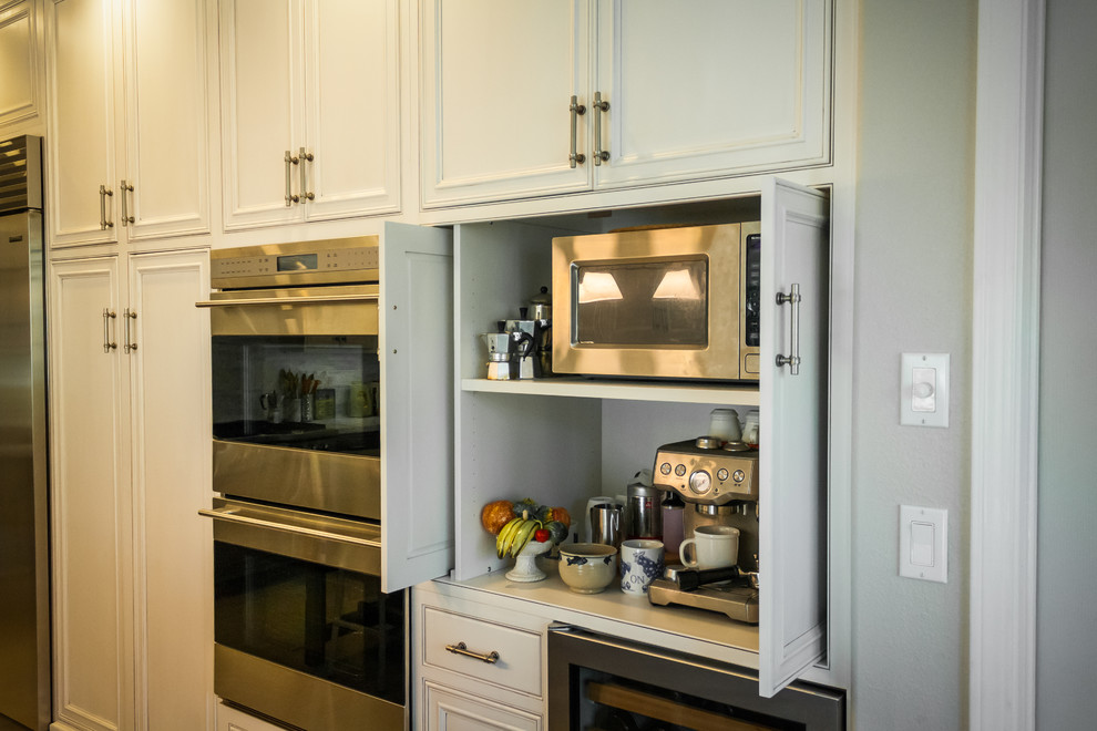 Foto de cocina de estilo de casa de campo con puertas de armario blancas, encimera de mármol, electrodomésticos de acero inoxidable y una isla
