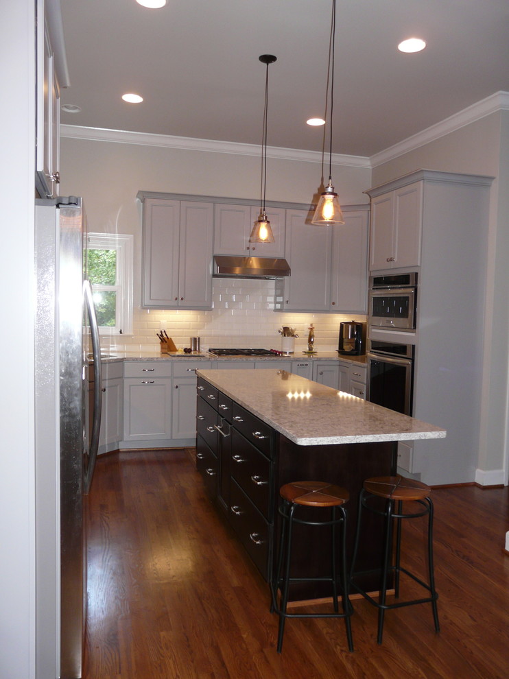 Example of a mid-sized transitional u-shaped medium tone wood floor eat-in kitchen design in Birmingham with an undermount sink, recessed-panel cabinets, gray cabinets, quartz countertops, subway tile backsplash, stainless steel appliances and an island