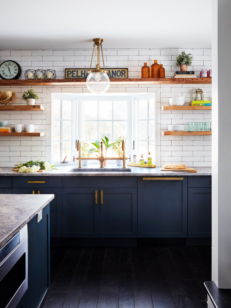 Bild på ett stort lantligt grå grått kök, med en undermonterad diskho, skåp i shakerstil, blå skåp, vitt stänkskydd, stänkskydd i tunnelbanekakel, färgglada vitvaror, mörkt trägolv, en köksö och svart golv