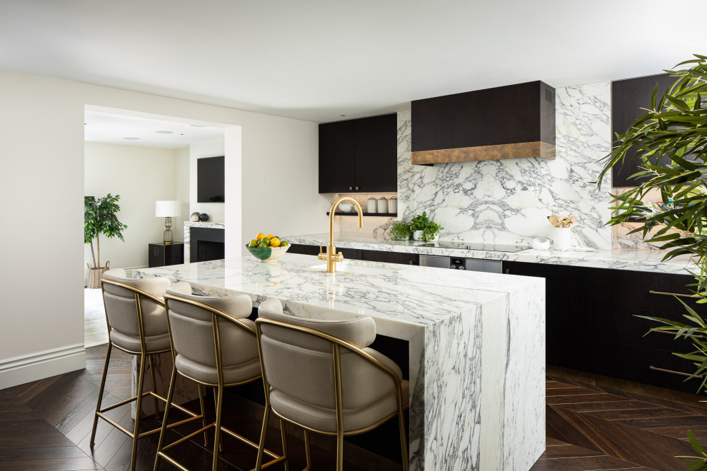Mid-sized trendy galley dark wood floor and brown floor eat-in kitchen photo in London with a drop-in sink, flat-panel cabinets, marble countertops, white backsplash, marble backsplash, stainless steel appliances, an island and white countertops