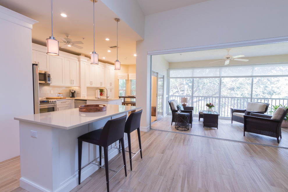 Example of a large transitional single-wall ceramic tile eat-in kitchen design in Miami with a single-bowl sink, shaker cabinets, white cabinets, quartz countertops, white backsplash, glass tile backsplash, stainless steel appliances and an island