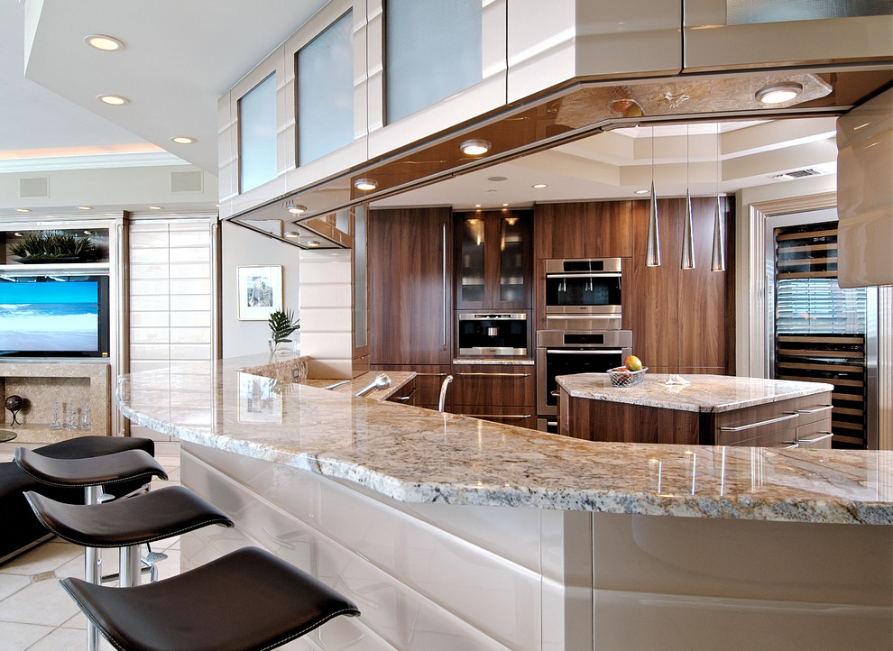 Geschlossene Moderne Küche in U-Form mit flächenbündigen Schrankfronten, hellbraunen Holzschränken, Granit-Arbeitsplatte, Küchengeräten aus Edelstahl, Kücheninsel und beigem Boden in Miami